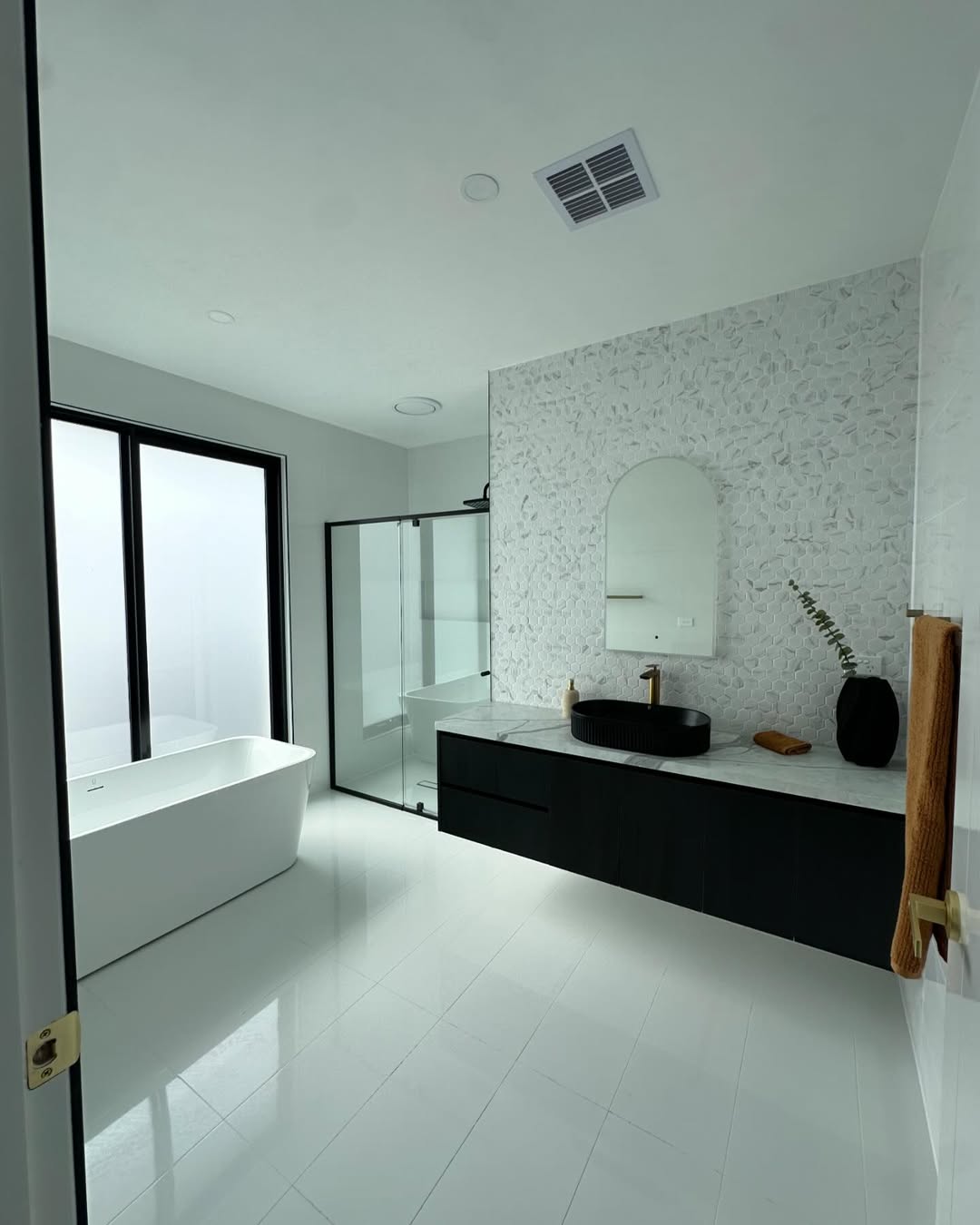Freestanding bath with black vanity and mosaic tiling